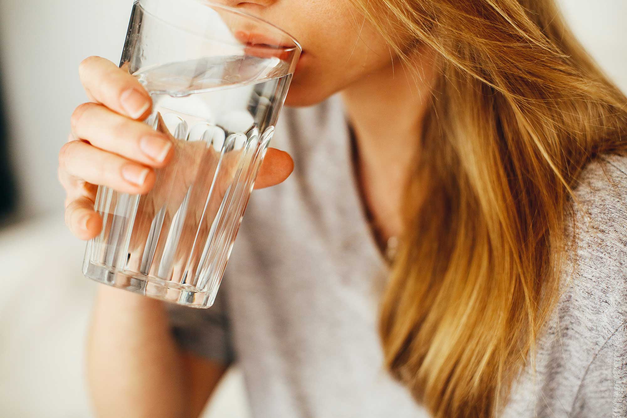 Eine junge Frau genießt einen köstlichen Schluck feinstes EAU~K